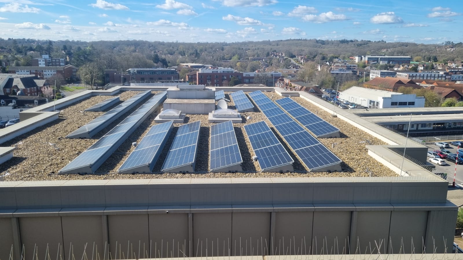 Aerial view of a cleaned commercial rooftop solar array above a Sussex town